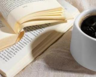 une tasse de café à côté de deux livres ouverts